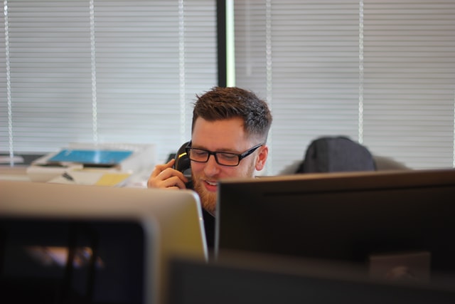 A man in the office talking on a phone.